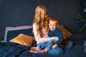 una giovane madre con un figlio piccolo seduto sul letto in un abbraccio foto