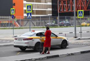 l'assistente di volo femminile aspetta il taxi vicino all'aeroporto foto