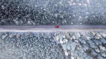 viaggi in auto su strada nella foresta invernale vista dall'alto dal drone. foto