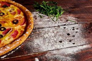 tavolo da cucina in legno con pizza spolverata di farina foto