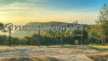 provincia di loei, tailandia dicembre 2021 cartello del parco nazionale di phu ruea con sfondo dell'alba mattutina e della bellissima valle al punto di vista in cima al parco nazionale di phu ruea. foto