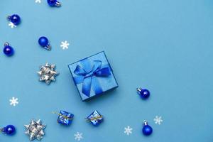 sfondo invernale blu. simpatica confezione regalo con nastro azzurro, palline di natale foto