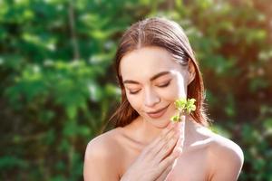 ritratto di una giovane donna con una foglia in mano sfondo naturale foto