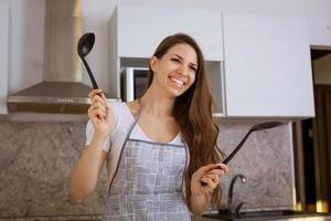 giovane donna in cucina con un mestolo in mano sorridente foto