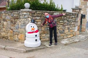 donna escursionista accanto al pupazzo di neve fatto di pneumatici foto