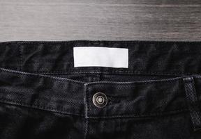 etichetta di abbigliamento in bianco sulla trama dei jeans denim. etichetta con spazio vuoto per il testo foto