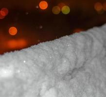 neve che cade di notte con un effetto bokeh su uno sfondo di luci della città. foto