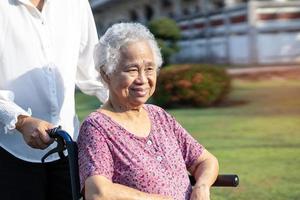 assistenza e cura del caregiver paziente asiatico anziano o anziano della donna che si siede sulla sedia a rotelle nel parco, concetto medico forte sano. foto