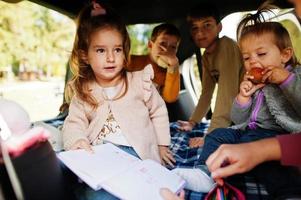 madre con quattro bambini all'interno del veicolo. bambini nel bagagliaio. viaggiare in auto, sdraiarsi e divertirsi, concetto di atmosfera. foto