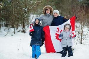 madre con bambini che tengono la bandiera del canada sul paesaggio invernale. foto