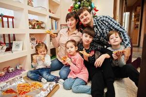 famiglia felice con quattro bambini che mangiano pizza a casa. foto