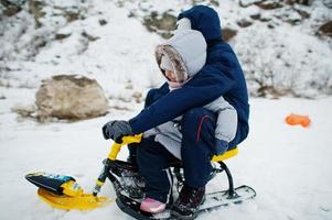 fratello e sorella si godono un giro in slitta. slittino per bambini. bambino in sella a una slitta in inverno. foto