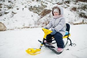 la bambina si gode un giro in slitta. slittino per bambini. bambino in sella a una slitta in inverno. foto