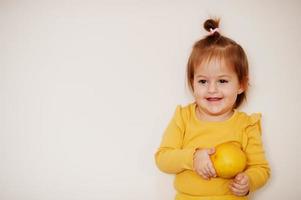 bambina in giallo con limone, sfondo isolato. foto