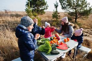 madre allegra con bambini a un picnic. famiglia in vacanza con frutta all'aperto. foto