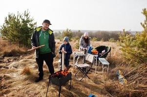 famiglia al barbecue su una terrazza nella pineta. giornata barbecue con griglia. foto