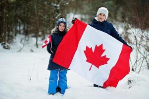 due ragazzi che tengono la bandiera del canada sul paesaggio invernale. foto