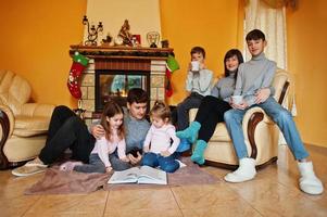 felice giovane famiglia numerosa a casa da un camino nel caldo soggiorno in una giornata invernale. foto