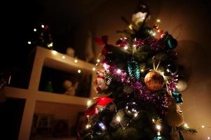 albero di natale con ghirlande brillanti sulla sera a casa. foto