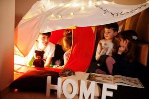 giocare ai bambini con il gattino in tenda di notte a casa. umore hygge. foto