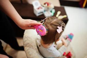 weekend di madre e figlia insieme a casa, mamma che fa l'acconciatura per la bambina. foto