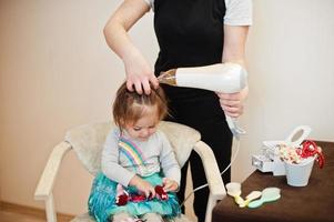 mamma con la figlia del bambino che fanno insieme la routine quotidiana. la madre sta spazzolando e asciugando i capelli del bambino dopo la doccia. foto