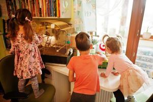 tre bambini che tengono in mano i loro animali preferiti. bambini che giocano con criceti, tartarughe e pappagalli a casa. foto