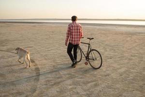 ciclista che cammina con la bici nera retrò durante l'alba nel deserto foto
