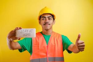 operaio edile asiatico tenere note e pollice in alto la mano sinistra foto