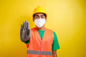 operaio edile asiatico che indossa una maschera protettiva facendo un gesto di arresto foto