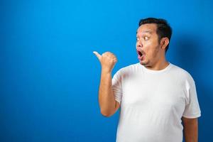 l'uomo asiatico grasso in maglietta bianca mostra un'espressione scioccata e sorpresa divertente su sfondo blu foto