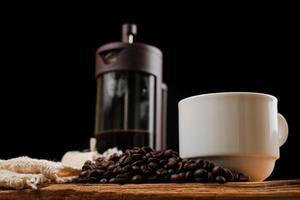 chicco di caffè con la tazza bianca sul tavolo di legno foto