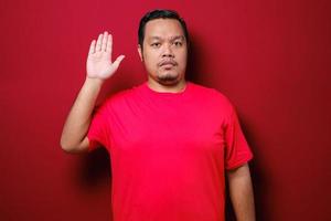 giovane uomo asiatico bello che indossa una t-shirt rossa in piedi su sfondo rosso isolato foto