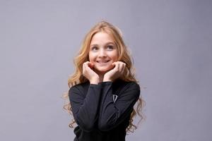 foto di sognante ragazza carina positiva con lunghi capelli biondi ondulati alla ricerca