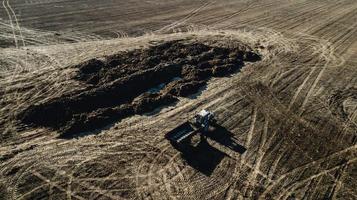 fertilizzante sul campo. trattore vicino al mucchio di letame. rilievo aereo foto