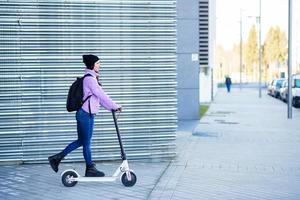 giovane donna sui vent'anni in sella a uno scooter elettrico. foto