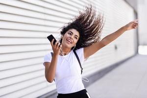 donna africana che ascolta musica con auricolari e smartphone foto