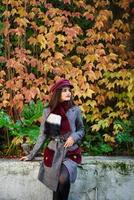 giovane bella ragazza con capelli molto lunghi che indossa cappotto invernale e berretto in autunno lascia lo sfondo foto