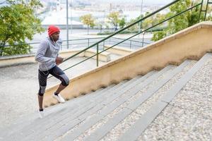 uomo di colore che corre al piano di sopra all'aperto in background urbano foto
