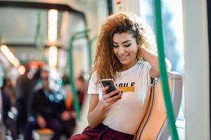 donna araba all'interno del treno della metropolitana guardando il suo smartphone foto