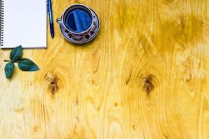 tazza di caffè e taccuino aperto su fondo di legno foto