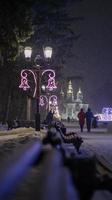 foto ravvicinata di un lampione al buio in inverno con fiocchi di neve che cadono. strada decorata per natale e capodanno. serata magica atmosfera. strada di notte. illuminazione stradale retrò.