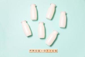 piccole bottiglie con probiotici e prebiotici latticini su sfondo blu. produzione con additivi biologicamente attivi. fermentazione e dieta cibo sano. yogurt bio con microrganismi utili. foto