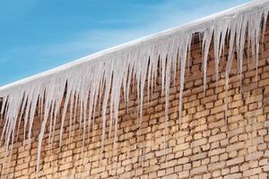 grandi ghiaccioli pericolosi sul tetto in una giornata invernale. foto