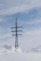 torre elettrica ad alta tensione tra cumuli di neve. foto