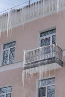 ghiaccioli taglienti pericolosi che pendono dal tetto e dal balcone. foto
