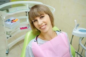donna felice che si siede nell'ufficio del dentista, denti sani foto