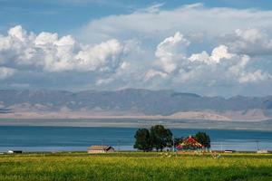 il cielo azzurro e le nuvole bianche accanto al lago qinghai, così come alcune tende e bandiere di preghiera sui prati foto