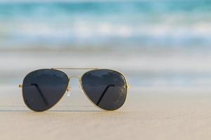 occhiali da sole sulla sabbia bella spiaggia estiva copia spazio concetto di vacanza. foto