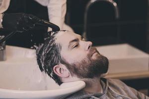 il barbiere lava i capelli di un uomo foto